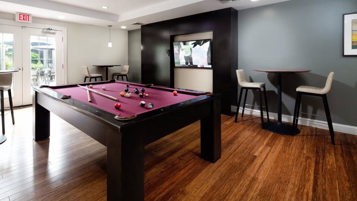 High tables and chairs with a billiard table and a tv mounted on a wall