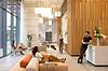 Residents relaxing and socializing in a modern lobby area with contemporary decor, including wood paneling, soft seating, and large windows