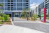 Entrance to the Cascade Link at Douglas apartment building, with landscaping, a parking sign, and a modern exterior visible on a bright, sunny day