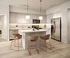 A modern kitchen featuring light wood cabinets, a center island with stools, stainless steel appliances, and pendant lighting.