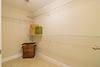 Empty closet with wire shelves, a wicker basket, and a green paper bag on the floor. Neutral walls and tile flooring.