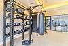 A modern gym interior featuring weight racks, medicine balls, a punching bag, and exercise ropes.