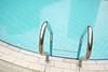 A close-up view of a swimming pool with a silver ladder and clear blue water.