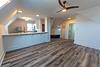 Bright, open living space with a kitchen bar, modern ceiling fan, and new flooring in a cozy, airy atmosphere.