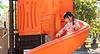 A young girl enjoys sliding down an orange playground slide on a sunny day.