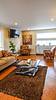 Modern living room with a couch, two patterned chairs, a coffee table, and a flat-screen TV, featuring warm colors.