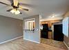 A spacious, well-lit kitchen area with a ceiling fan, black appliances, and light wooden flooring.