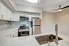 A kitchen featuring stainless steel appliances, a sink, and white cabinetry with gray backsplash tiles.