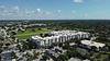 Aerial view of urban development, green park space, and surrounding buildings under a partly cloudy sky.