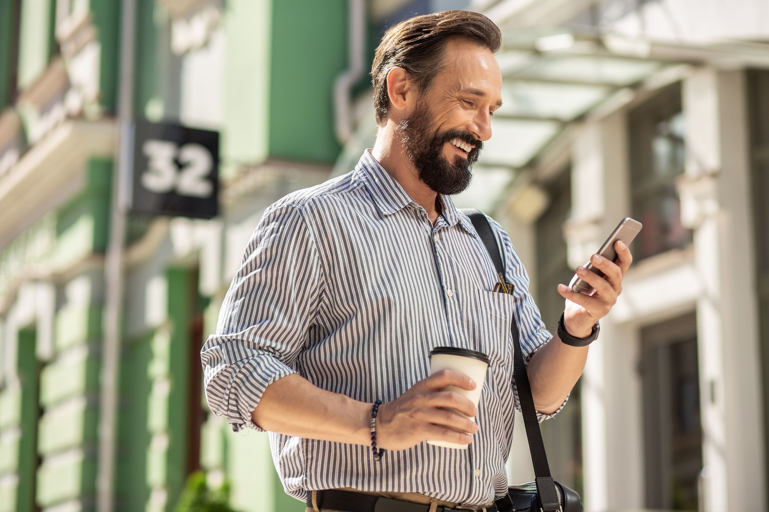 Man smiling at phone walking down street