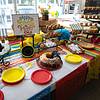 Dessert table with colorful Mexican table cloth, red and yellow plates, donuts, pies, and cookies.