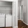 Side by side washer and dryer inside of a closet in hallway with hard surface flooring