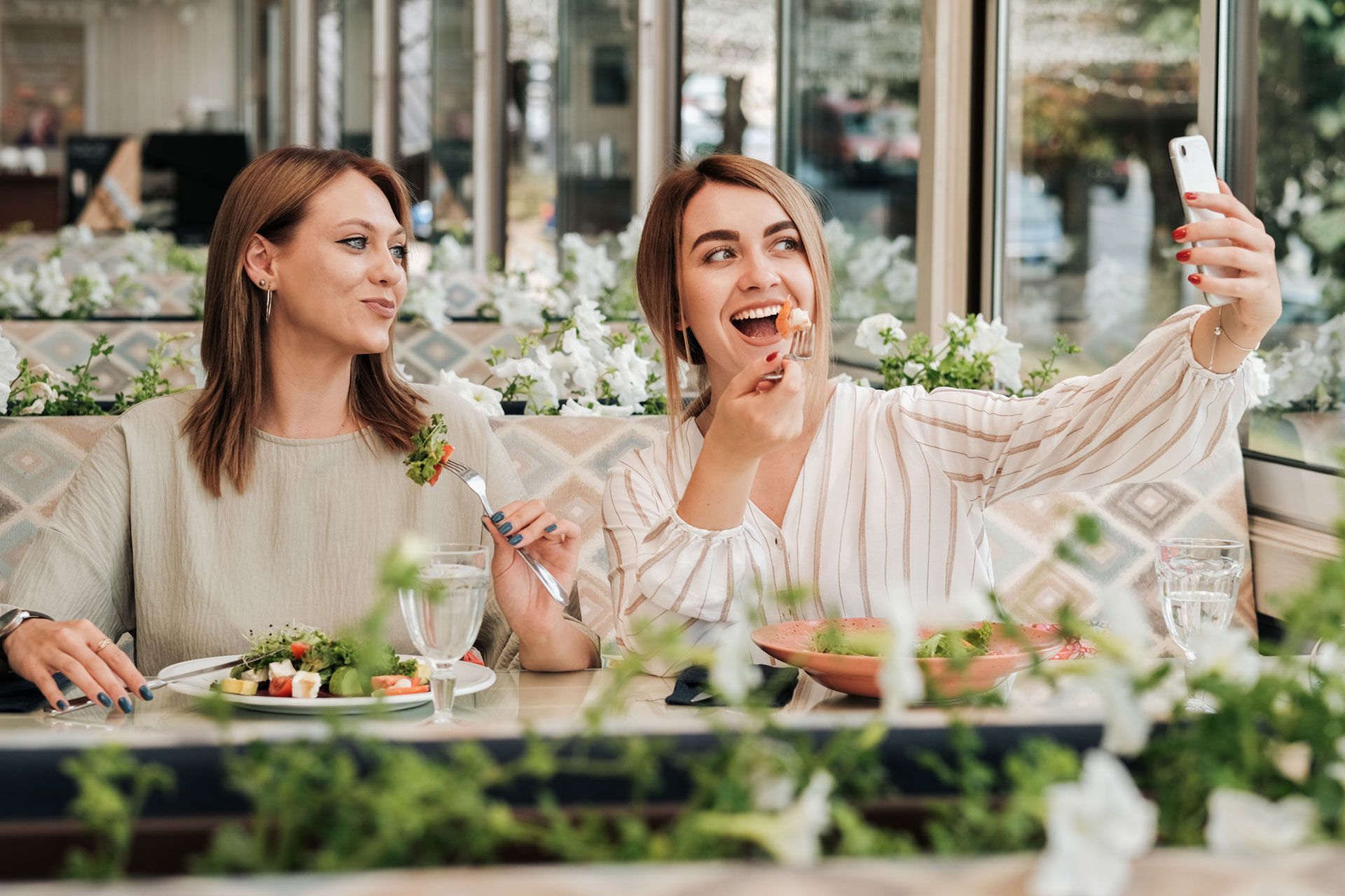 two-women-making-selfie-while-having-lunch-meeting-female-friends-eating-salad-in-the-restaurant