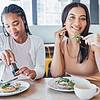 a couple of women sitting at a table with food