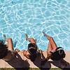 ladies on the side of a pool with their feet in the pool