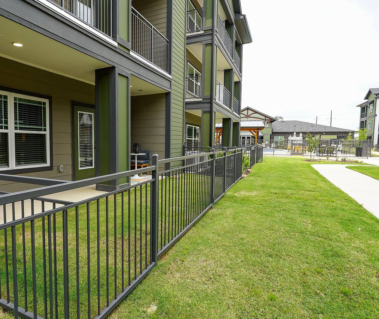 A modern kitchen with dark cabinets, stainless steel appliances, and a large island, featuring hardwood-style flooring.
