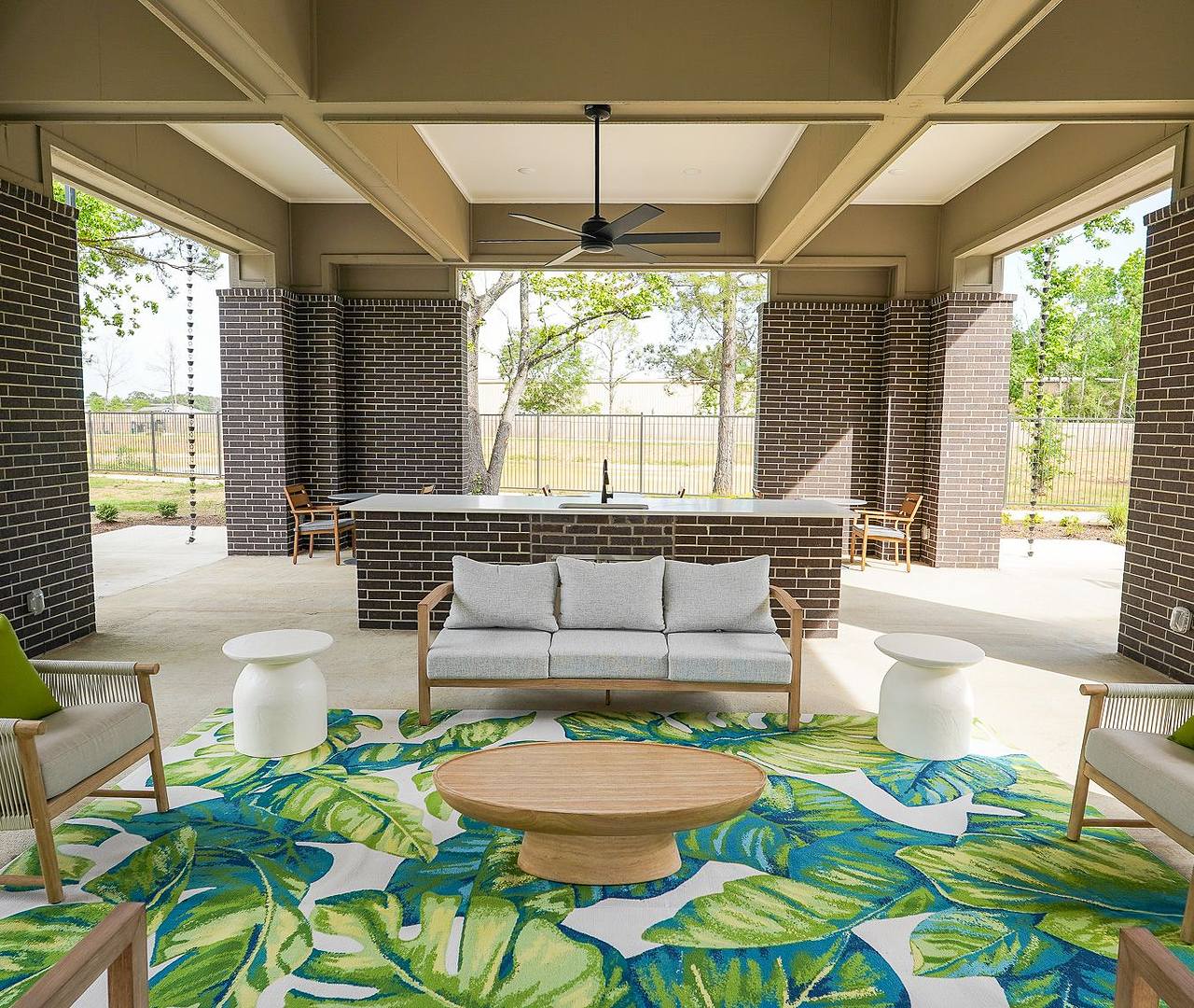 Three people sit by a pool, dipping their feet in the water, enjoying a sunny day.