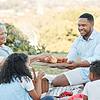 A group of people enjoying a picnic, sharing food, and smiling in a sunny outdoor setting.