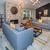 Modern living room with gray sofas, a stone fireplace, stylish lighting, and decorative accents on a patterned rug.
