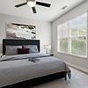 Bedroom with wood-style flooring, a ceiling fan, 9-foot ceilings, large windows, a large grey bed and modern wall art at Realm at Patterson Place Apartments.