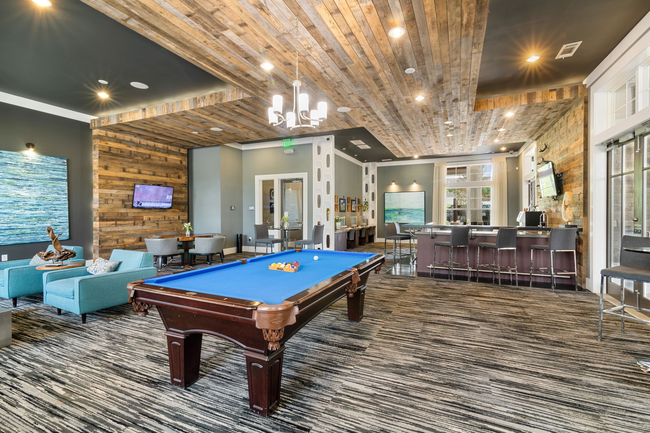 Resident game room with Billiards with wooden floors and stylish turquoise furniture at Patterson Place Apartments.