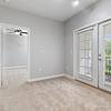 Bedroom with carpet, a ceiling fan, and white, French doors leading to a balcony at Patterson Place Apartments.
