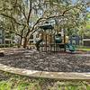 Wood chip playground with a play structure and large tree