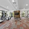 24-Hour Fitness Center with floor-to-ceiling windows and a wall-mounted television at Lantower Grande Flats Apartments.
