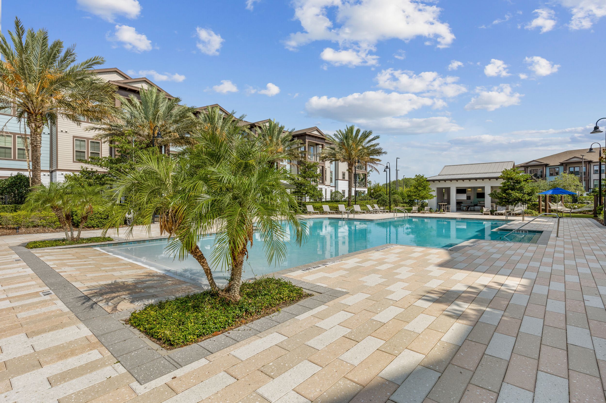 Resort-like pool with palm trees, a sundeck, and private cabanas at Lantower Grande Flats Apartments.