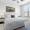 Spacious bedroom with lots of room for furniture, has a dark wood-style ceiling fan, large window for natural lighting, and hardwood flooring at Lantower Residences at the Collection