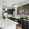 Chef-inspired kitchen with brushed nickel fixtures, 9-foot ceilings, Arctic Ice Quartz countertops and a kitchen island at Lantower Brandon Crossroads decorated with modern barstools and a bowl of fruit. 