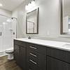Modern, clean bathroom with dark-colored cabinetry, brushed nickel fixtures, and a walk-in, glass door shower at Lantower Brandon Crossroads.