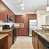 Modern kitchen with glossy countertops, stainless steel appliances, and wood cabinets at Lantower The Cortona