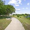 Sidewalk with scenic views of a pond fountain, park benches, and trees and green grass with ample room for outdoor activities at Lantower The Cortona