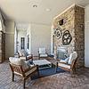 Outdoor lounging area with brick flooring and a brick fireplace, comfortable seating, and decorative wall art at Lantower The Cortona