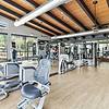 Spacious wood-style flooring with spaced out gym equipment, large mirrors, and windows at Lantower Legacy Lakes