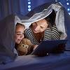 mother and daughter looking at a tablet under the covers