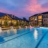 Resort-style pool with a sunny deck and ample relaxing seating at sunset hour. 