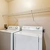 In-unit laundry room with attached washer, dryer, and wire shelving.