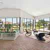 Lantower Tortuga Bay sun room with plenty of seating, large floor to ceiling windows with beautiful scenic views, brick floors, and fan.	