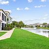 Lush landscaping with palm trees, green grass, and water front feature at Tortuga Bay Apartments in Orlando, FL.	