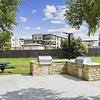 fenced in, grass outdoor area with a circular table and cement floored grilling area at Lantower Round Rock