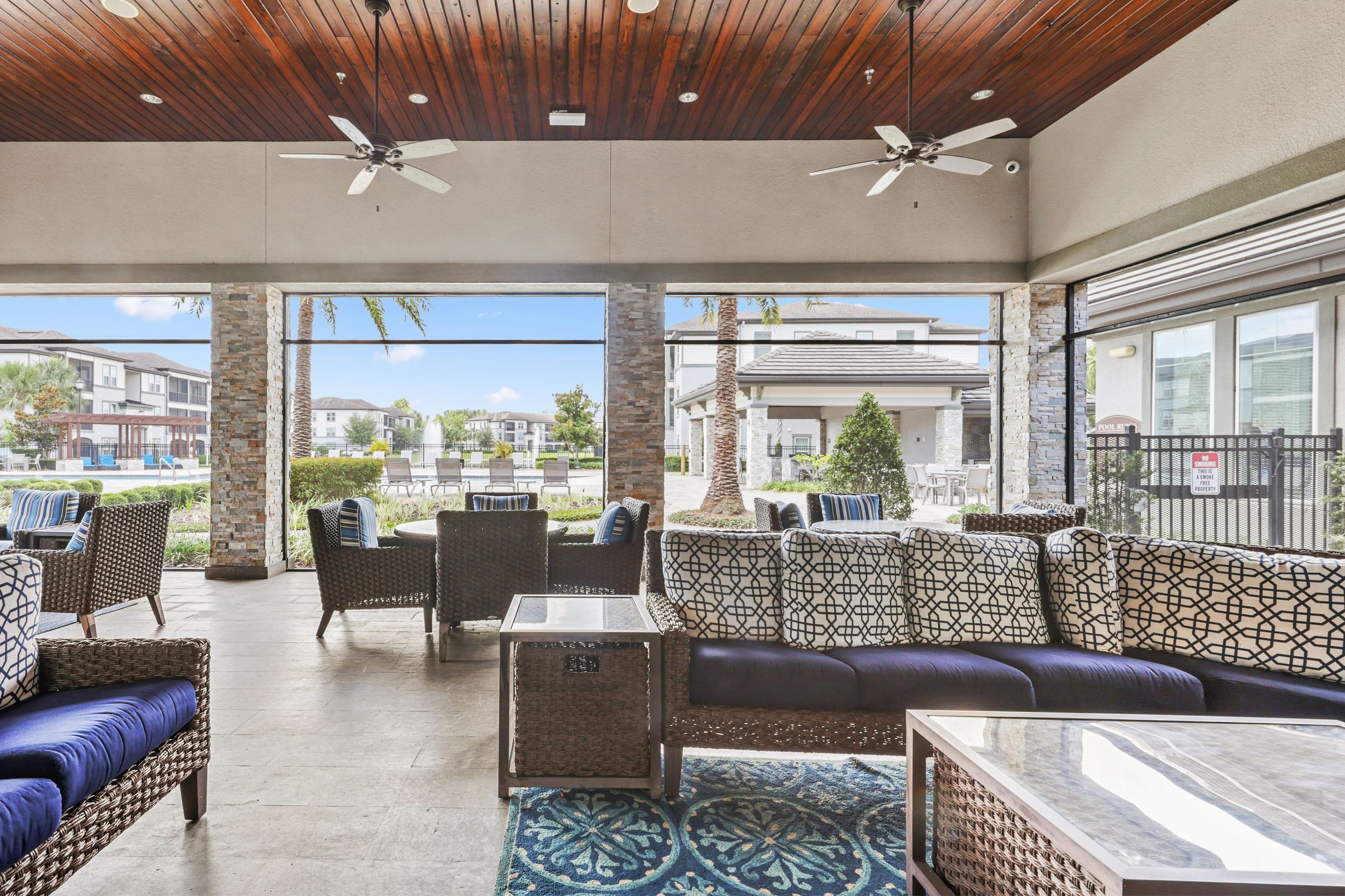 Spacious, covered veranda with natural sunlight, a fireplace, and stylish furniture at Lantower Grande Pines.