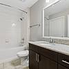 Large and bright bathroom with granite countertop, espresso-colored cabinetry, double sinks, large mirror, tile flooring, and tiled shower tub combo at Lantower Westshore.