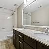 Large and bright bathroom with granite countertop, espresso-colored cabinetry, double sinks, large mirror, tile flooring, and tiled shower tub combo at Lantower Westshore.