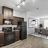 Open and spacious kitchen and living room with dark stained-wood cabinets, black stainless steel appliances, a large window for natural lighting and plenty of room for furniture at Lantower Techridge