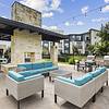 Outdoor poolside lounge area with comfortable sofas and chairs, grills, string lights and a brick fireplace at Lantower Techridge apartments