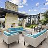 Outdoor poolside lounge area with sofas and chairs, grills, string lights and a brick fireplace at Lantower Techridge apartments