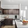 Modern kitchen fit with diamond white quartz countertops and stainless steel sink basin, stainless steel appliances, and an island with overhead lighting at Lantower Techridge apartments