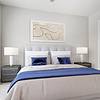 Spacious bedroom with 10-foot ceilings, wood-style floors, large floor-to-ceiling windows and modern cream and blue bedding at Lantower Weston Corners. 